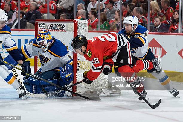 Marcus Kruger of the Chicago Blackhawks attempts to get the puck past goalie Brian Elliott of the St. Louis Blues as Jaden Schwartz pushes behind in...