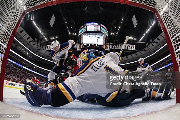 Colton Parayko of the St. Louis Blues and Marcus Kruger of the Chicago Blackhawks chase the puck in front of goalie Brian Elliott during Game Four of...