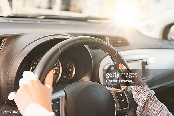woman holding steering wheel and driving car during day - steering wheel stock pictures, royalty-free photos & images