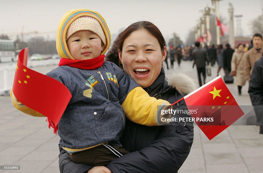 A mother carries her child waving Chines
