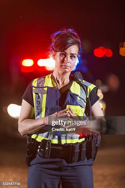 policewoman in street at night, police car in background - female police officer stock pictures, royalty-free photos & images