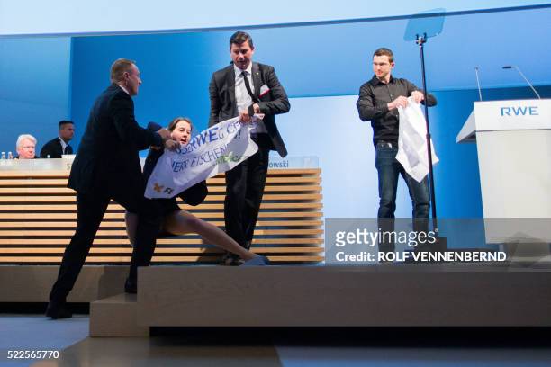 Security guards take an environmental activist from the stage after she demonstrated during the annual general meeting of German energy giant RWE in...