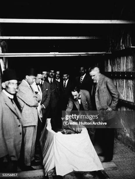 British archaeologist Howard Carter with members of his team and Egyptian officials inspect the mummy of the Pharaoh Tutankhamun inside the royal...