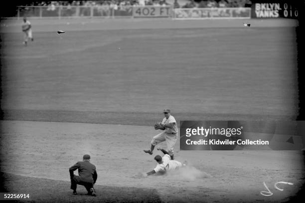Shortstop Pee Wee Reese of the Brooklyn Dodgers attempts to turn the double play as Enos Slaughter of the New York Yankees slides into second base...