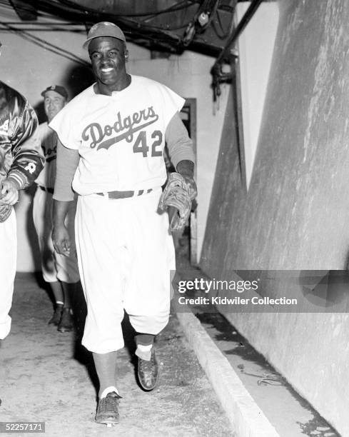 Infielder Jackie Robinson of the Brooklyn Dodgers happily returns to the clubhouse after the Dodgers beat the New York Yankees, 1-0, in Game 6 of the...