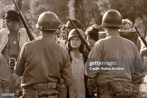 Young female protester wearing a helmet faces down helmeted and armed police officers at an anti-Vietnam War demonstration outside the 1968...