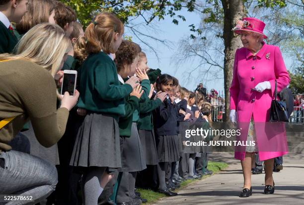 Britain's Queen Elizabeth II smiles as she is greeted by school children as she arrives to open a bandstand at Alexandra Gardens in Windsor, west of...