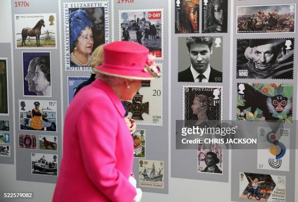 Britain's Queen Elizabeth II looks at a display of images of Royal Mail postage stamps, some depicting members of the Royal Family, including the...