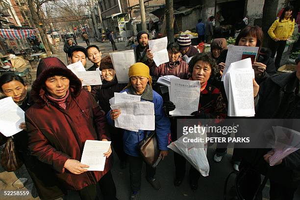 People hold up there petitions in a squatter village in southern Beijing 01 March 2005 where people from all over China have come to air their...