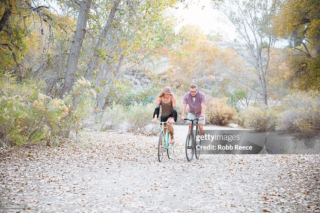 A young, happy man and woman riding bicycles in a park for fitness