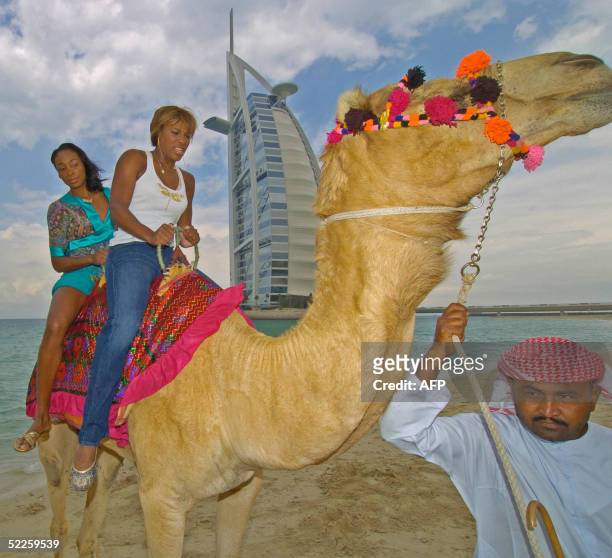 Tennis champions Serena and her sister Venus Williams ride a camel on the beach in front of the Burj Al Arab hotel during the WTA Dubai Women's Duty...