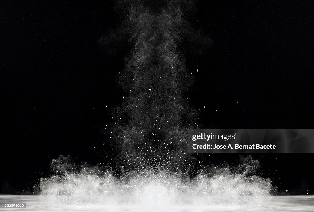 Blackground of particles of white powder in ascending movement floating in the air