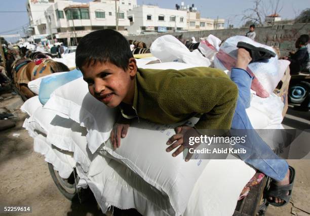 Palestinian refugee boy plays on flour bags after his family and others received aid food from the European Union, distributed by the World Food...