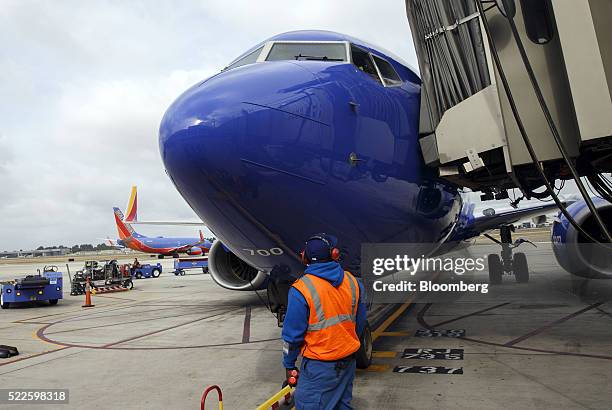 Ground operations employee prepares a Southwest Airlines Co. Boeing Co. 737 aircraft for departure on the tarmac at John Wayne Airport in Santa Ana,...