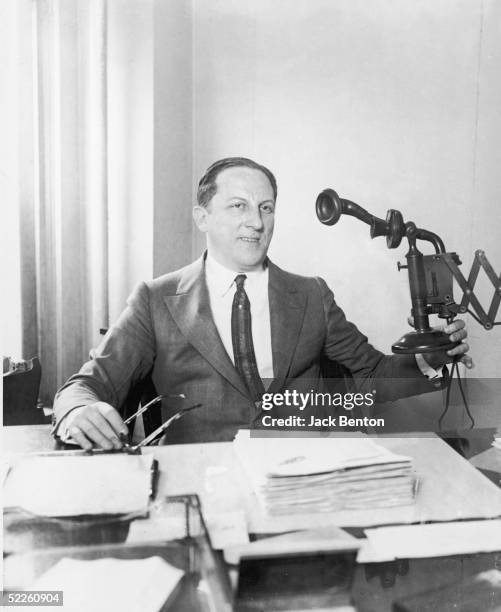 American professional gambler Arnold Rothstein sits at his desk holding a wall-mounted telephone, circa 1915. Rothstein was accused of masterminding...