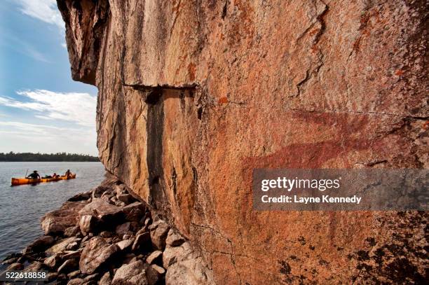 canoeists paddle by pictographs on lac la croix lake - boundary waters canoe area stock pictures, royalty-free photos & images