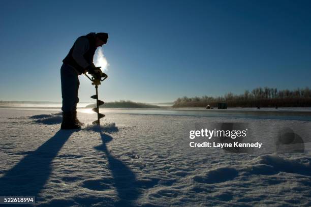 ice fisherman drilling hole in ice on the missouri river - ice fishing stock pictures, royalty-free photos & images