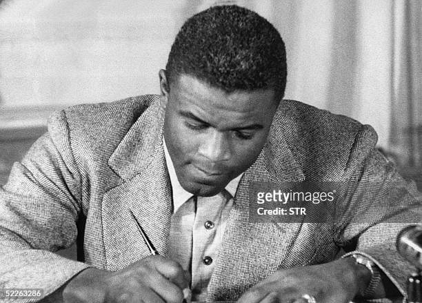 This undated file photo shows US baseball star Jackie Robinson as he signs a then-record contract to play for the Brooklyn Dodgers in New York....