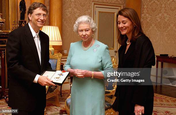 Britain's Queen Elizabeth II presents Microsoft tycoon Bill Gates with his honorary knighthood watched by his wife Melinda Gates on March 2, 2005 at...