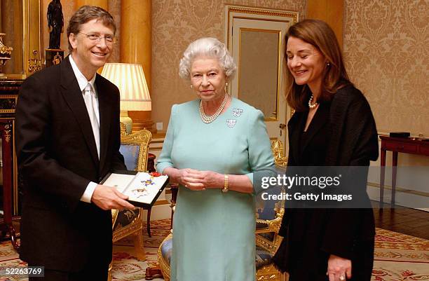 Britain's Queen Elizabeth II presents Microsoft tycoon Bill Gates with his honorary knighthood watched by his wife Melinda Gates on March 2, 2005 at...
