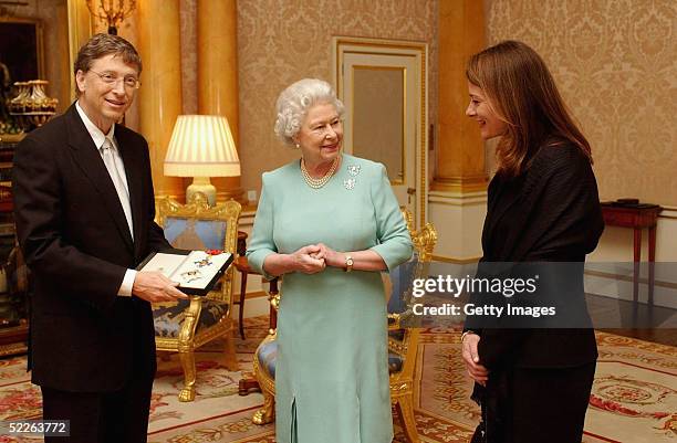 Britain's Queen Elizabeth II presents Microsoft tycoon Bill Gates with his honorary knighthood watched by his wife Melinda Gates on March 2, 2005 at...