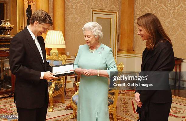 Britain's Queen Elizabeth II presents Microsoft tycoon Bill Gates with his honorary knighthood watched by his wife Melinda Gates on March 2, 2005 at...
