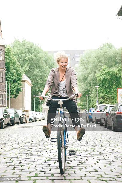 young woman having fun riding her bike in city streets - legs spread woman stock pictures, royalty-free photos & images