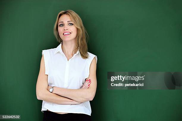 smiling beautiful teacher at blackboard - green blouse stock pictures, royalty-free photos & images