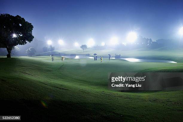golfing at night in guangdong province - golf caddy stockfoto's en -beelden