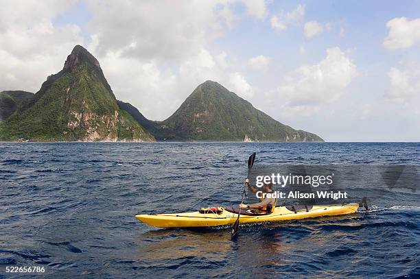 kayaker passing piton mountains on st. lucia - pitons stock pictures, royalty-free photos & images