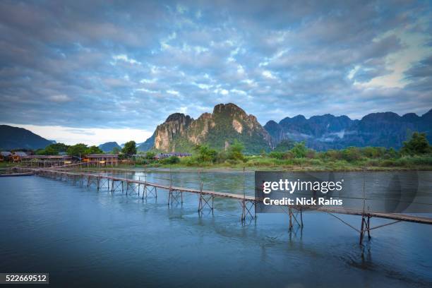 footbridge over nam song river at vang vieng in laos - laos stock pictures, royalty-free photos & images