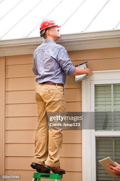 inspector or blue collar worker examines building roof outdoors. - roofing contractor stock pictures, royalty-free photos & images