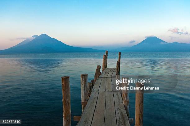 pier on lake atitlan with view of volcanoes - lake atitlan stock pictures, royalty-free photos & images