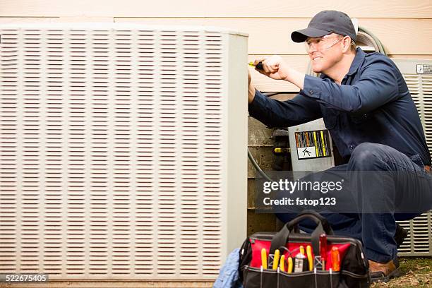 air conditioner repairman works on home unit. blue collar worker. - luftkonditioneringsanläggning bildbanksfoton och bilder