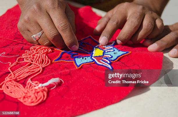 man's hands sewing a mexican cultural design on red fabric. - costurar - fotografias e filmes do acervo