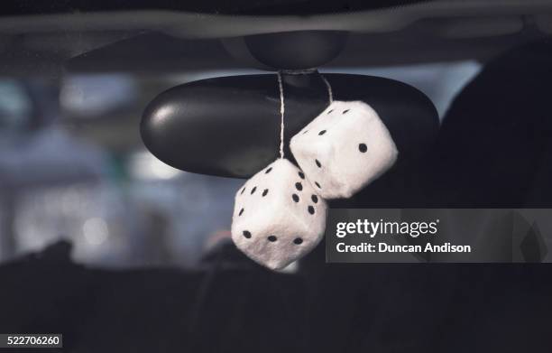 fluffy dice hanging off the rear view mirror of a car. - car decoration stock pictures, royalty-free photos & images