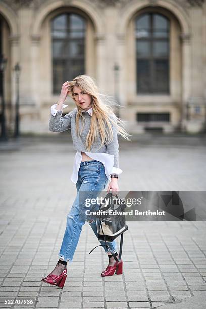 Emma Bonneaud , is wearing Zara red shoes, Mango blue jeans, a Wanted Gina white shirt, an Asos gray pullover, a Daniel Wellington watch, a Zara bag,...