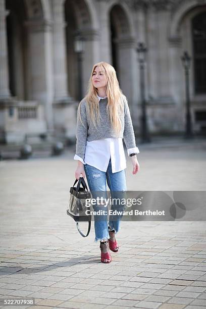 Emma Bonneaud , is wearing Zara red shoes, Mango blue jeans, a Wanted Gina white shirt, an Asos gray pullover, a Daniel Wellington watch, a Zara bag,...