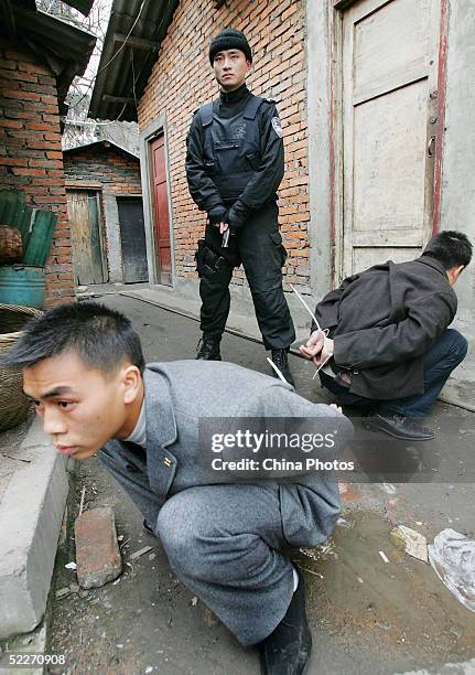 Policeman escorts suspects arrested for stealing bicycles at a residential area on March 3, 2005 in Chengdu of Sichuan Province, China. Police...