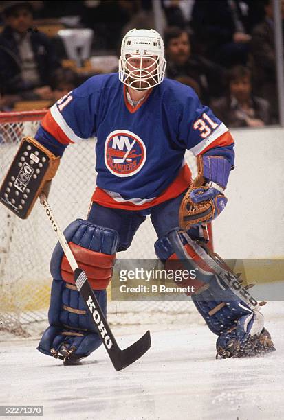 Canadian hockey player Billy Smith in the uniform of the New York Islanders, guards the net during a road game, 1980s.