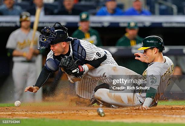 Chris Coghlan of the Oakland Athletics scores on a double by Josh Reddick as catcher Brian McCann of the New York Yankees reaches back for the ball...