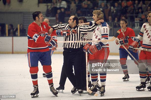 Canadian hockey player Frank Mahovlich of the Montreal Canadiens argues with Vic Hadfield of the New York Rangers as linesman John D'Amico tries to...