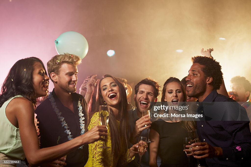 Cheerful friends having champagne on dance floor