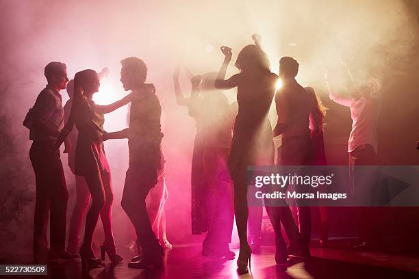 people dancing at nightclub - rave party photos et images de collection