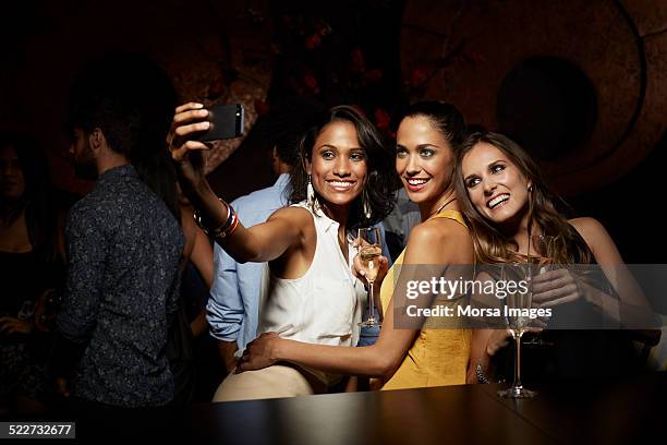 happy women taking self portrait at nightclub - glamour fotografías e imágenes de stock