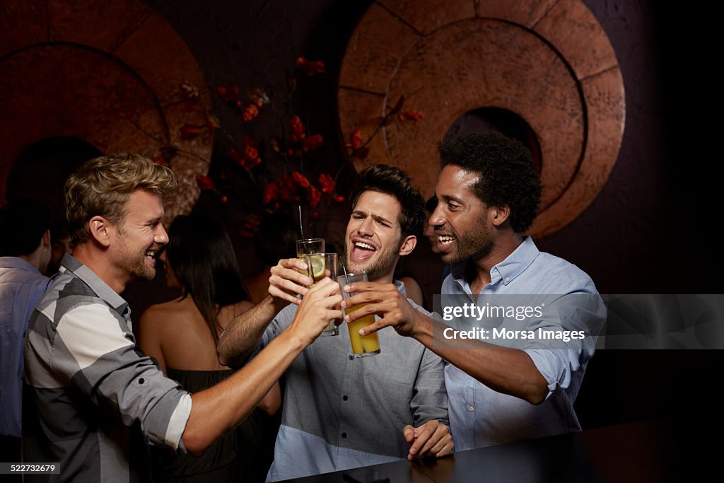 Cheerful friends toasting drinks in nightclub