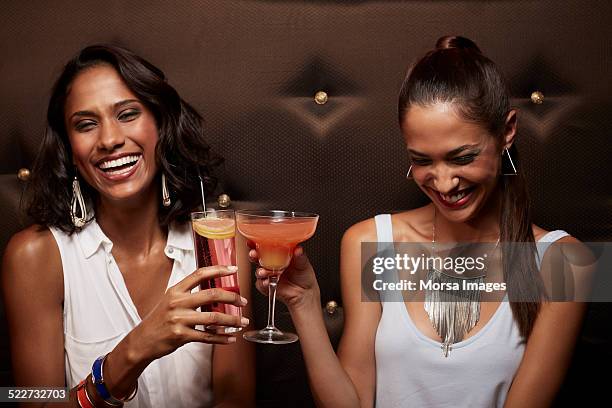 cheerful women toasting drinks at nightclub - friendship necklace stock-fotos und bilder