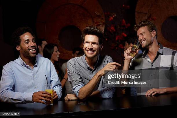 cheerful friends enjoying drinks in nightclub - bancone bar foto e immagini stock