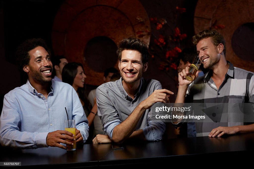 Cheerful friends enjoying drinks in nightclub