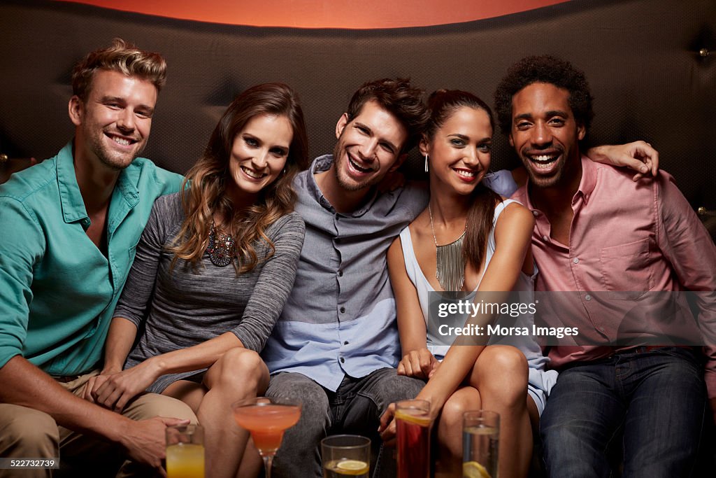 Cheerful friends sitting on sofa at nightclub